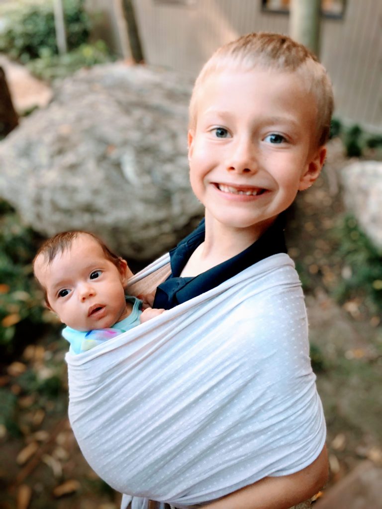 Tania's son Lucas carrying his little sister in a baby carrier.